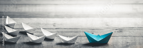 Fotografía Blue Paper Boat Leading A Fleet Of Small White Boats On Wooden Table With Vintag
