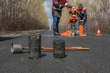 Worker Cut By The Core Sampler Samples Of Asphalt Concrete On The Road. Asphalt Concrete Cores Close-up