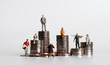 Coin piles and miniature people. Concepts about the poor and the rich.