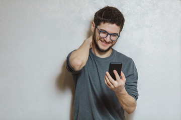 Portrait of young man using smartphone, over white textured background.
