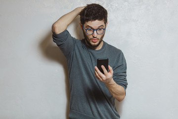 Portrait of young man using smartphone, over white textured background.