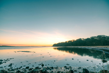 Wall Mural - lake in the sunrise with rocks on the beach