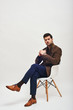 © Friends Stock - I'm listening to you. Stylish dark-haired man sitting on a chair and looking at camera isolated over white background