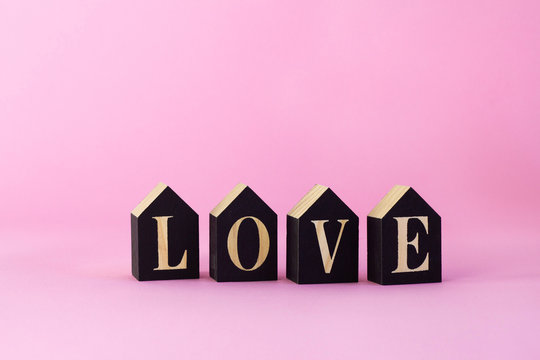 Word love on black wooden blocks with pink background, low angle view