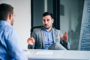 Handsome man talking to his employee on a meeting.