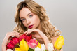 © LIGHTFIELD STUDIOS - young nude tender attractive spring woman touching bouquet of colorful tulips isolated on grey