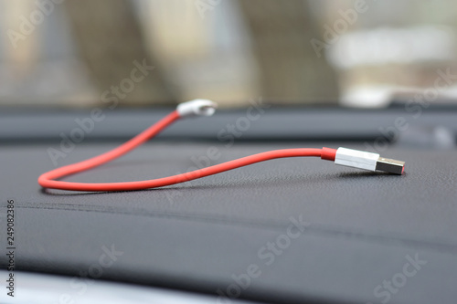 Red Charger Usb Cable With Selective Focus On Blurred Car