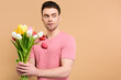 © LIGHTFIELD STUDIOS - surprised man holding bouquet of tulips isolated on beige