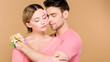 © LIGHTFIELD STUDIOS - handsome man hugging attractive girlfriend with flowers on face isolated on beige