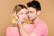 © LIGHTFIELD STUDIOS - handsome man touching face of  girlfriend with flowers on face isolated on beige