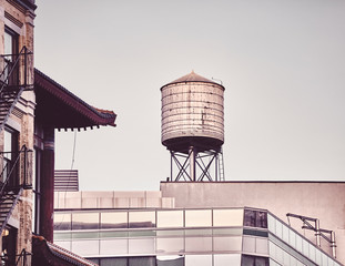 Retro toned picture of a rooftop water tower in downtown New York, USA.