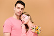 © LIGHTFIELD STUDIOS - woman embracing handsome man with flowers on hand isolated on beige
