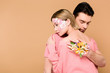 © LIGHTFIELD STUDIOS - man with closed eyes embracing woman with flowers on face isolated on beige
