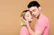 © LIGHTFIELD STUDIOS - tender man with alstroemeria flowers on hand touching face of attractive girlfriend isolated on beige