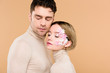 © LIGHTFIELD STUDIOS - handsome man standing with pretty girlfriend with closed eyes isolated on beige