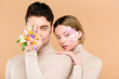 © LIGHTFIELD STUDIOS - man with alstroemeria flowers on hand covering one eye near attractive girlfriend with flowers on face isolated on beige
