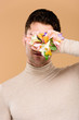 © LIGHTFIELD STUDIOS - man with alstroemeria flowers on hand covering face isolated on beige