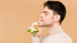 © LIGHTFIELD STUDIOS - side view of handsome man with alstroemeria flowers on hand showing hush sign isolated on beige
