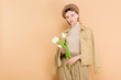 © LIGHTFIELD STUDIOS - attractive woman wearing beret and holding bouquet isolated on beige