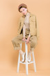 © LIGHTFIELD STUDIOS - stylish woman wearing beret and sitting on chair isolated on beige