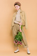 © LIGHTFIELD STUDIOS - stylish girl in beret standing with bouquet isolated on beige