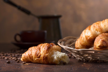 Fresh and tasty croissant  and cup of coffee on old copper background.