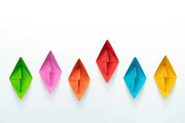 Multicolored paper boats on a white background, business competition concept with copy space