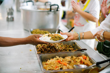 Volunteer food servers dish out a free charity : concept of helping