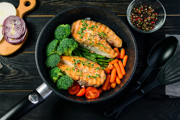 grilled salmon fillet with broccoli and vegetables in a pan