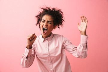 Poster - Beautiful young african woman posing isolated over pink wall background screaming singing.