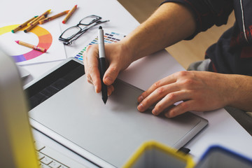 Wall Mural - Young Handsome Graphic designer using graphics tablet to do his work at desk