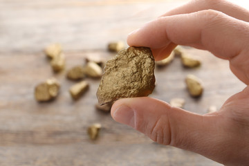 Man holding gold nugget on blurred background, closeup