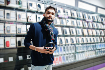 Indian beard man customer buyer at mobile phone store with wireless earphones. South asian peoples and technologies concept. Cellphone shop.