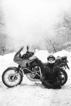 Rider Man And Adventure Motorcycle. Snowy Day. Meditating In The Lotus Position That Used To End The Winter. Travel Tour, Back And White. Winter Clothes, Equipment, Vertical Photo