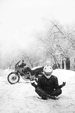 Rider Man And Adventure Motorcycle. Snowy Day. Meditating In The Lotus Position That Used To End The Winter. Travel Tour, Back And White. Winter Clothes, Equipment, Vertical Photo