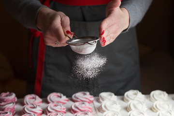 process of making marshmallow. Close up hands of the chef with metal sieve sprinkling zephyr with Powdered sugar at pastry shop kitchen. confectioner sprinkles sugar powder confectionery