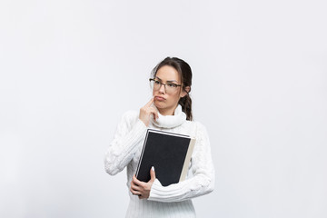 beautiful young woman in a studio with a book and glasses thinking