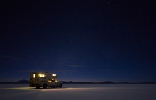 Illuminated Campervan On Salt Lake Under Starry Sky