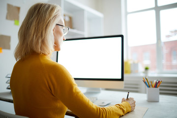 back view portrait of mature businesswoman using computer sitting at desk in office, copy space