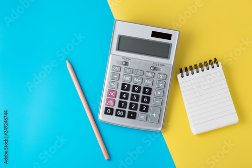 Fotografía Calculator and notepad on light blue and yellow background