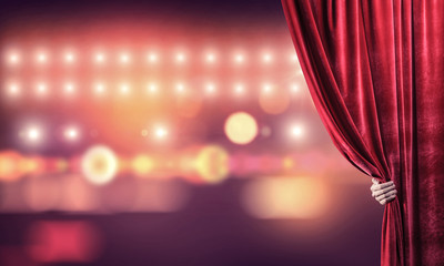 Bokeh lights behind drapery curtain and hand opening it