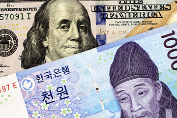 A macro image of a blue American one hundred dollar bill with a South Korean one thousad won note