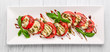 Caprese salad with mozzarella, tomato, basil and balsamic vinegar arranged on white plate