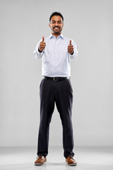 Wall Mural - business, office worker and people concept - smiling indian businessman showing thumbs up over grey background