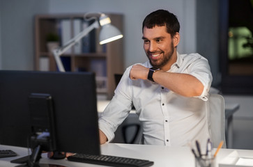 Canvas Print - business, technology and time management concept - happy businessman using voice command recorder on smart watch at nigh office