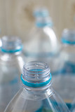 Fototapeta Miasto - Pack of transparent empty pet plastic water botles with blue label, no cap and blurred background