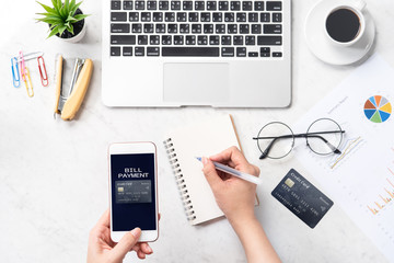 Concept of a woman is doing a online purchase, mock up card and cellphone on office desk isolated on beautiful fashion marble background, copy space, top view, flat lay, closeup