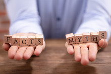 Businessman Balancing Facts And Myths Blocks On His Palm