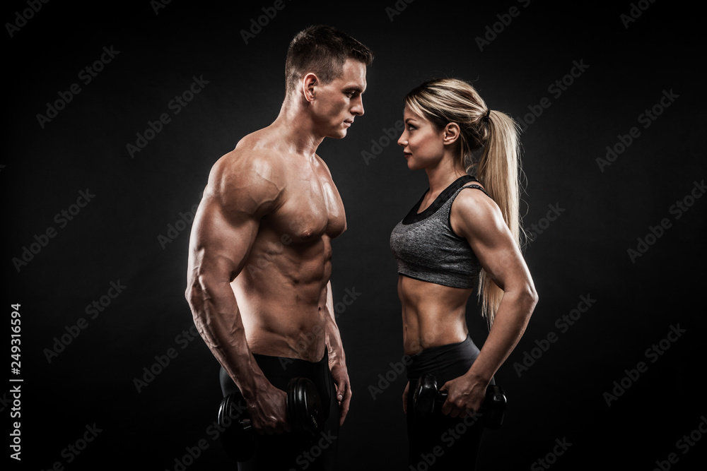 Sporty young couple posing on black background - obrazy, fototapety, plakaty 