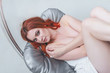 Beautiful naked woman lying with raised legs on a gray mattress hanging seat, white cloth. Women's health. sexuality.
